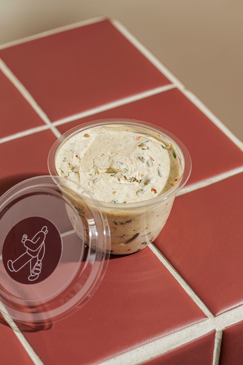 Jalapeño Cream Cheese pot with speckled green herbs and chilli, JUNTO branded lid alongside.