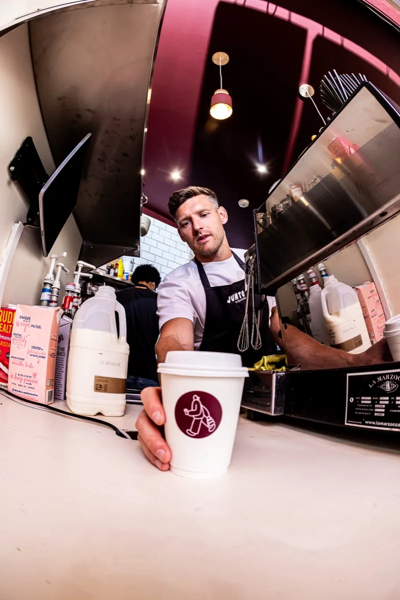Barista passing a takeaway coffee across the counter.