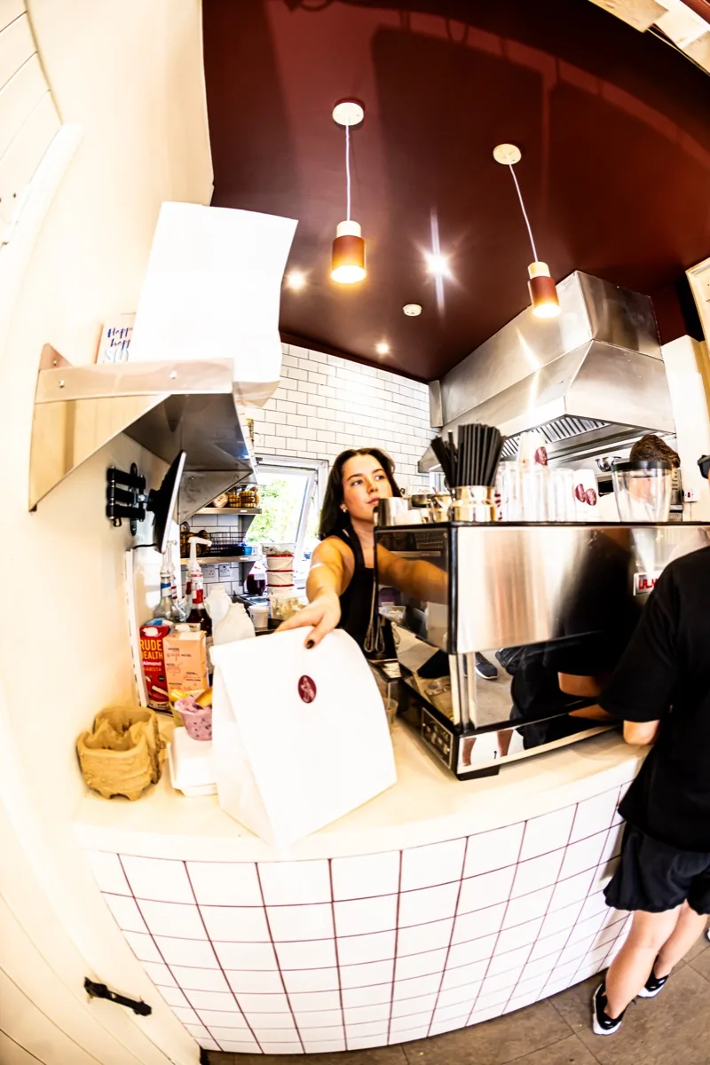 Team member handing a takeaway bag across the counter.
